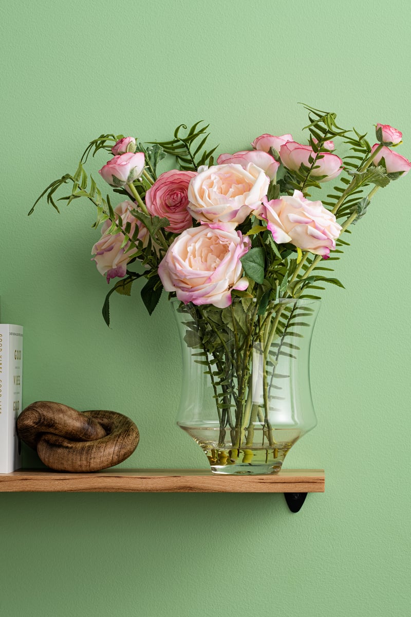 Pink and cream roses sit in vase with faux greenery on wood wall shelf